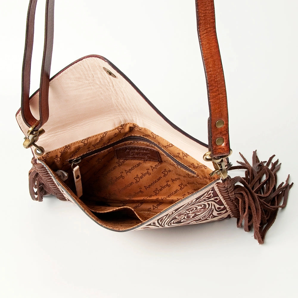 Inside view of brown leather handbag with intricate designs and tassels on a white background