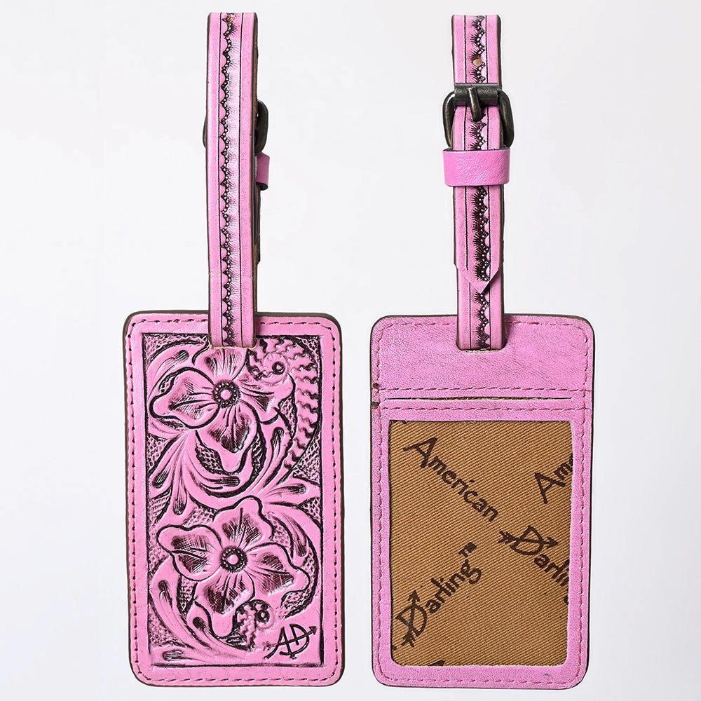 Back and front view of pink leather luggage tags with floral tooling on the left tag and a tan branded insert window on the right tag, shown against a plain white background.