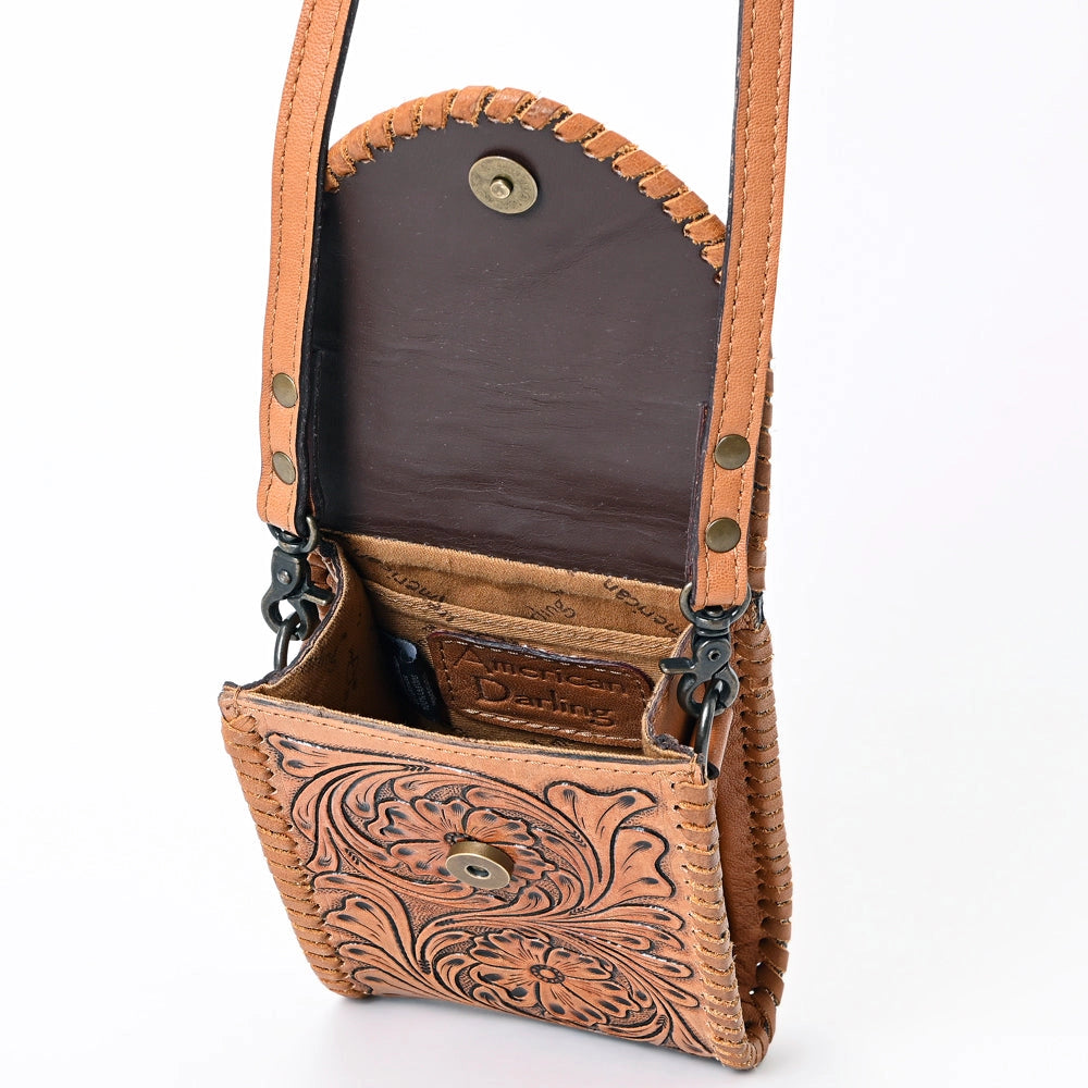 A small tooled leather crossbody bag in tan with a dark brown interior lining, shown open against a white background.