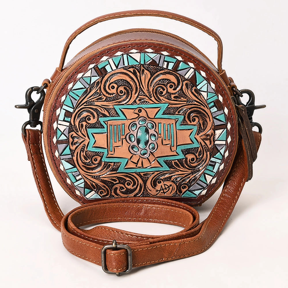 Round leather bag with intricate designs and a brown strap on a white background