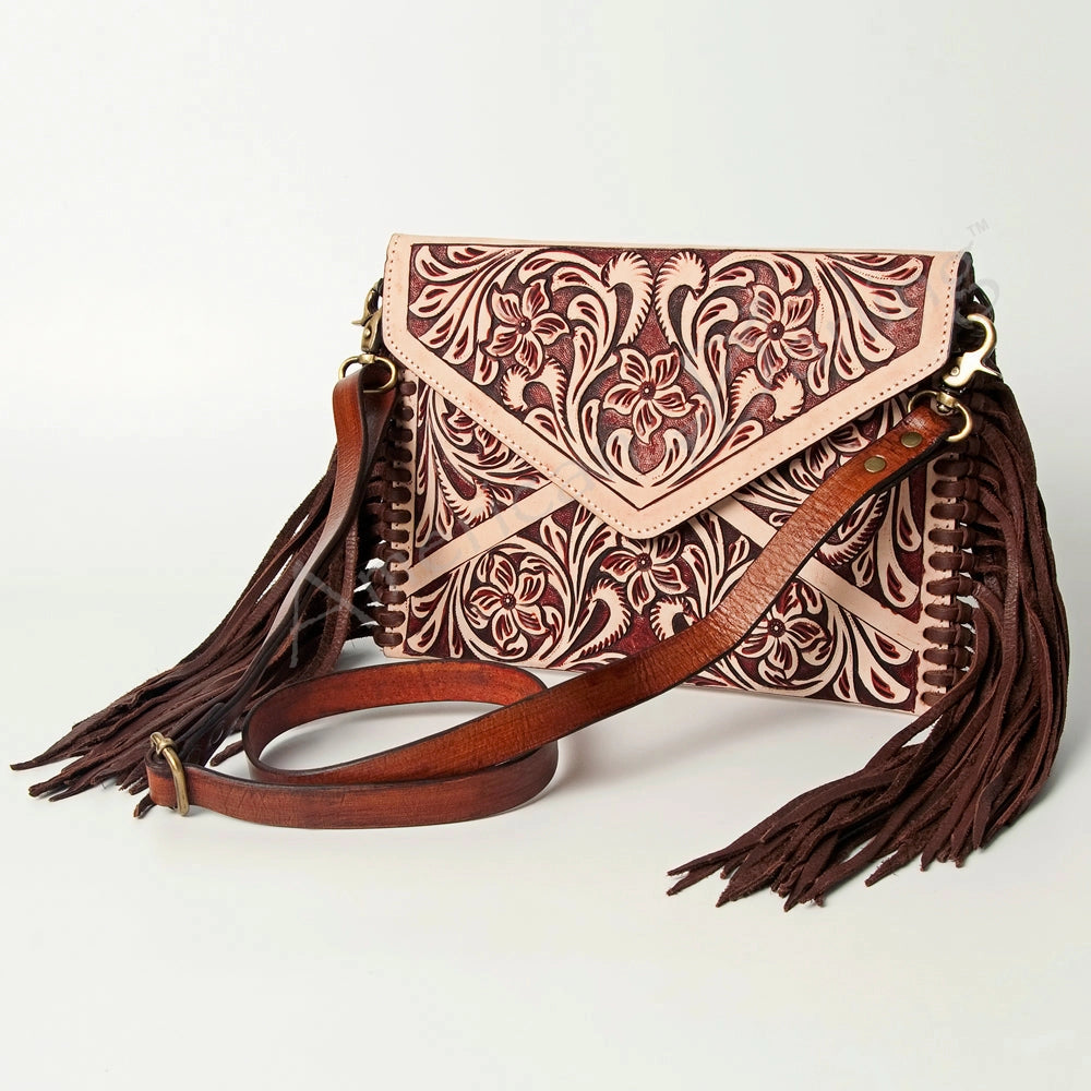 Brown leather handbag with intricate floral patterns and tassels on a light gray background