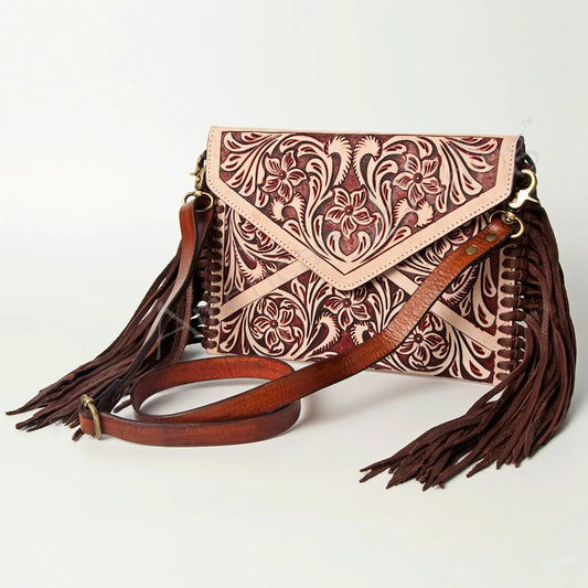 Brown leather handbag with intricate floral patterns and tassels on a light gray background