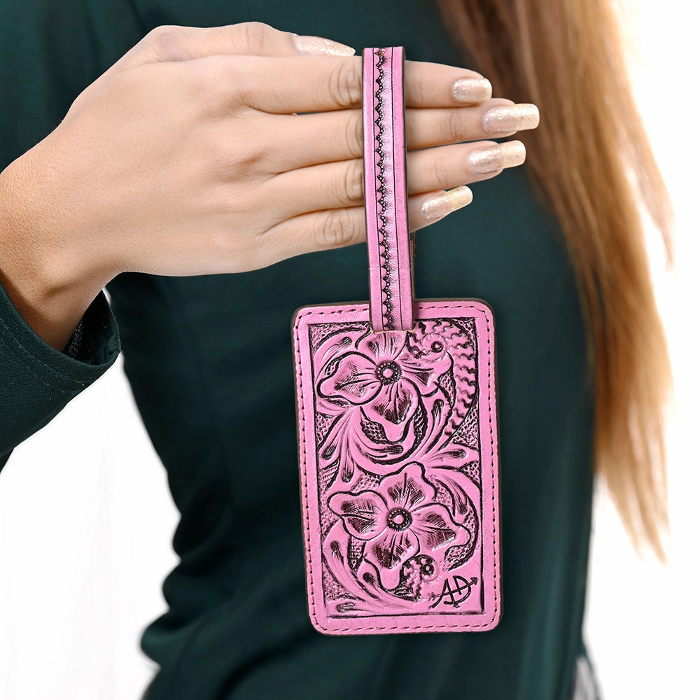 Pink leather luggage tag with floral patterns held by a person