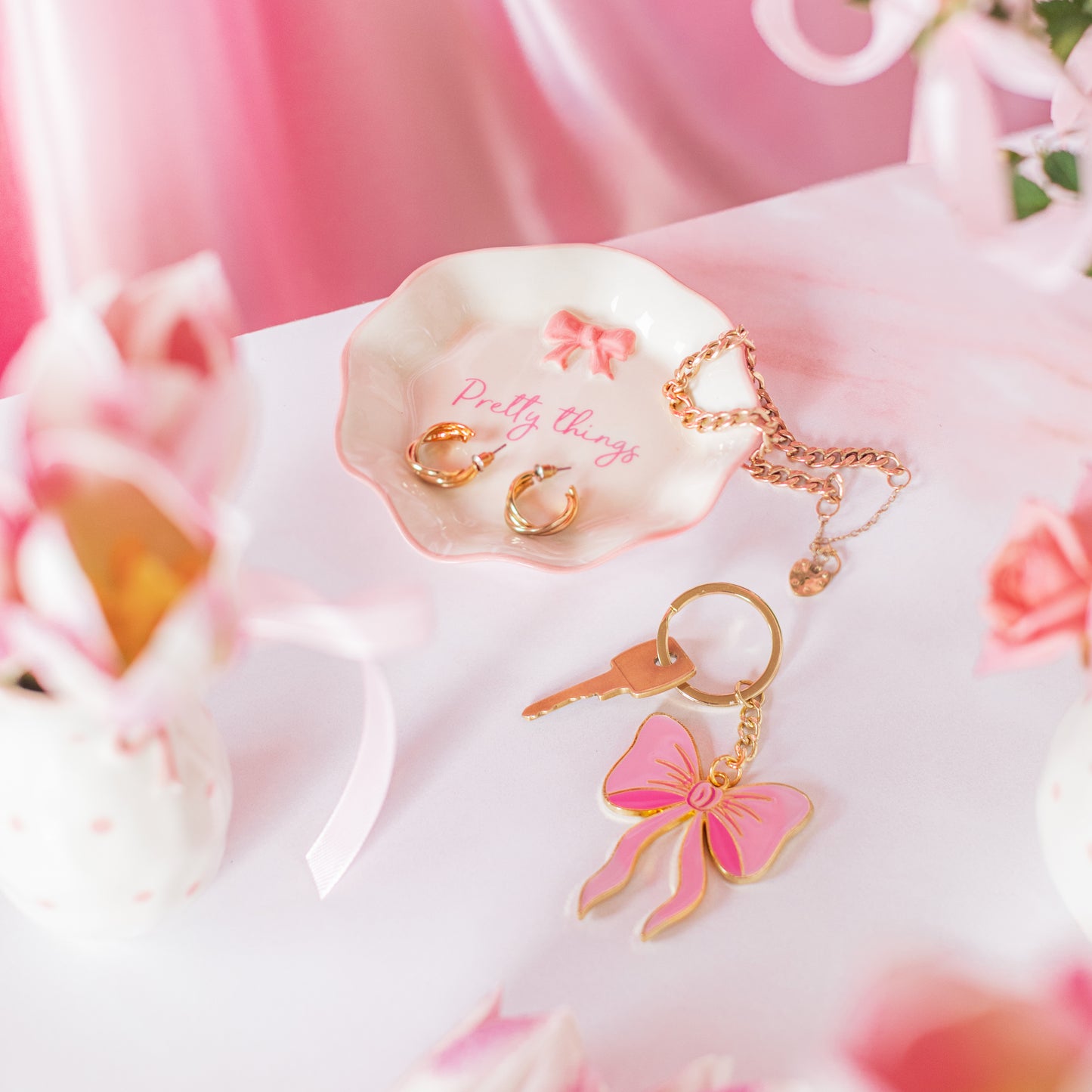 Gold key-shaped keychain with pink bow on a pink floral background
