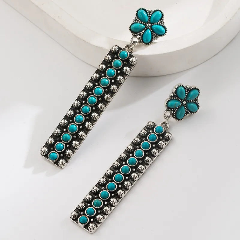 Lovely turquoise and stainless steel drop earrings featuring a slower and a long oblong drop embellished with turquoise.