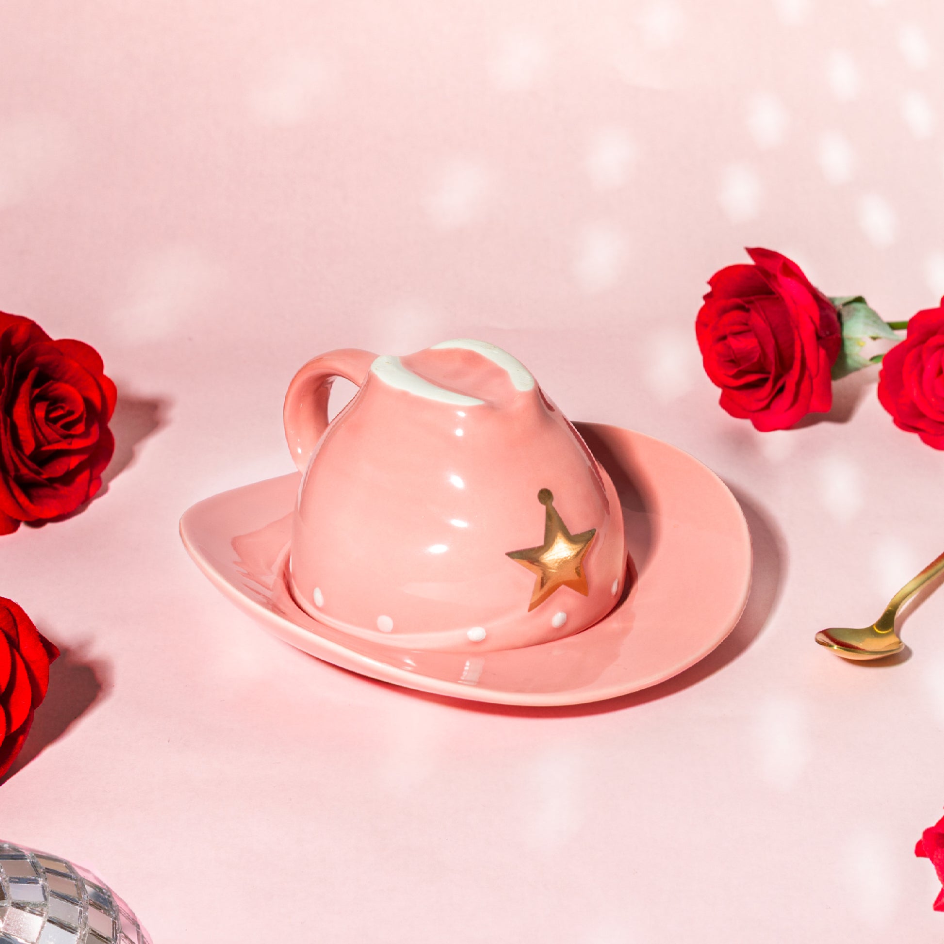 Pink teacup with star design on a pink background with red roses