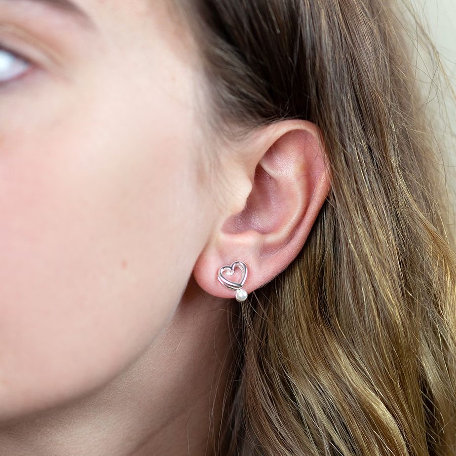 Double layer heart stud earrings with white faux pearls.being worn