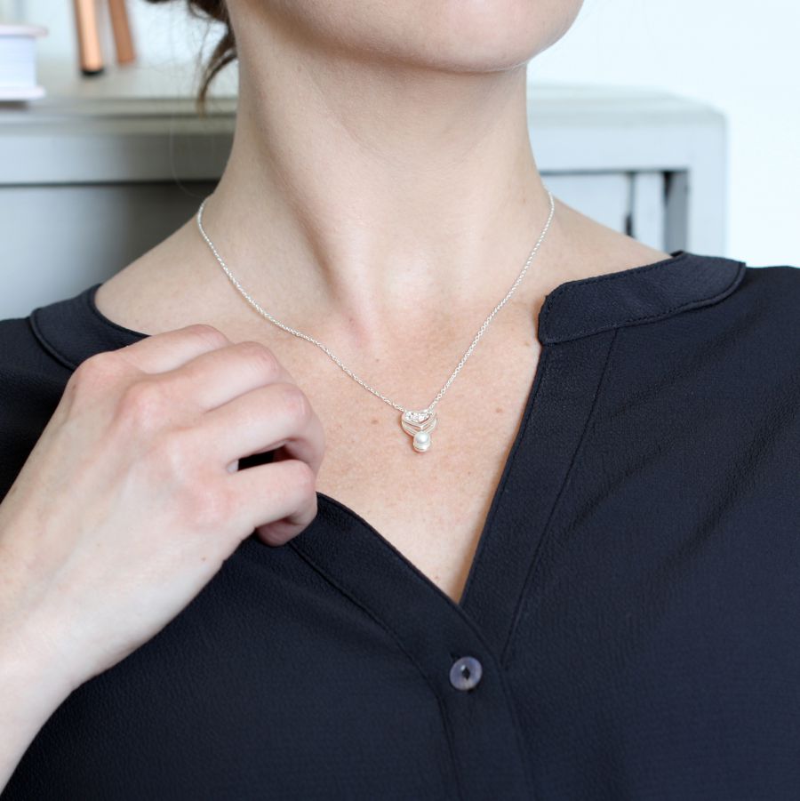 Fine chain silver plated necklace with a double layer open heart and a single white faux pearl bring worn