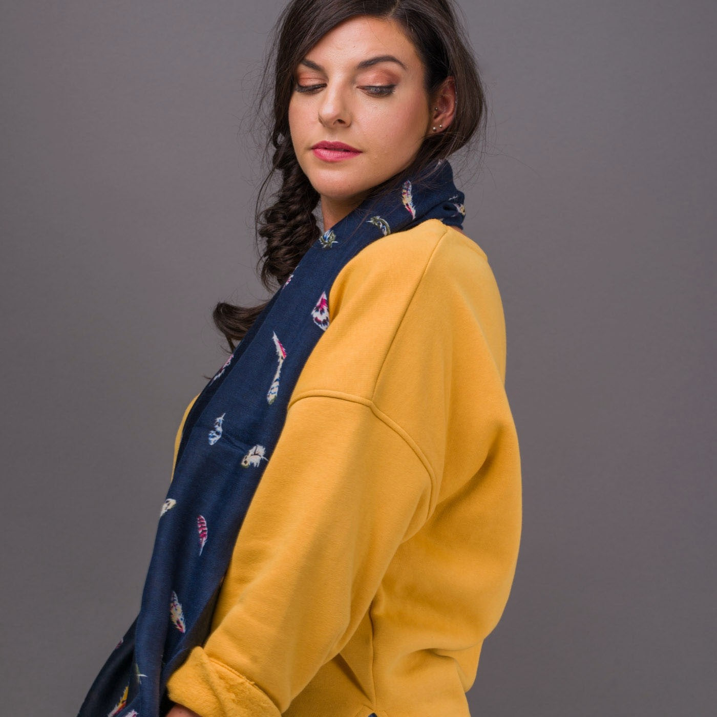 Gorgeous dark blue scarf featuring a colourful floating feather design that is perfect for the colder seasons.